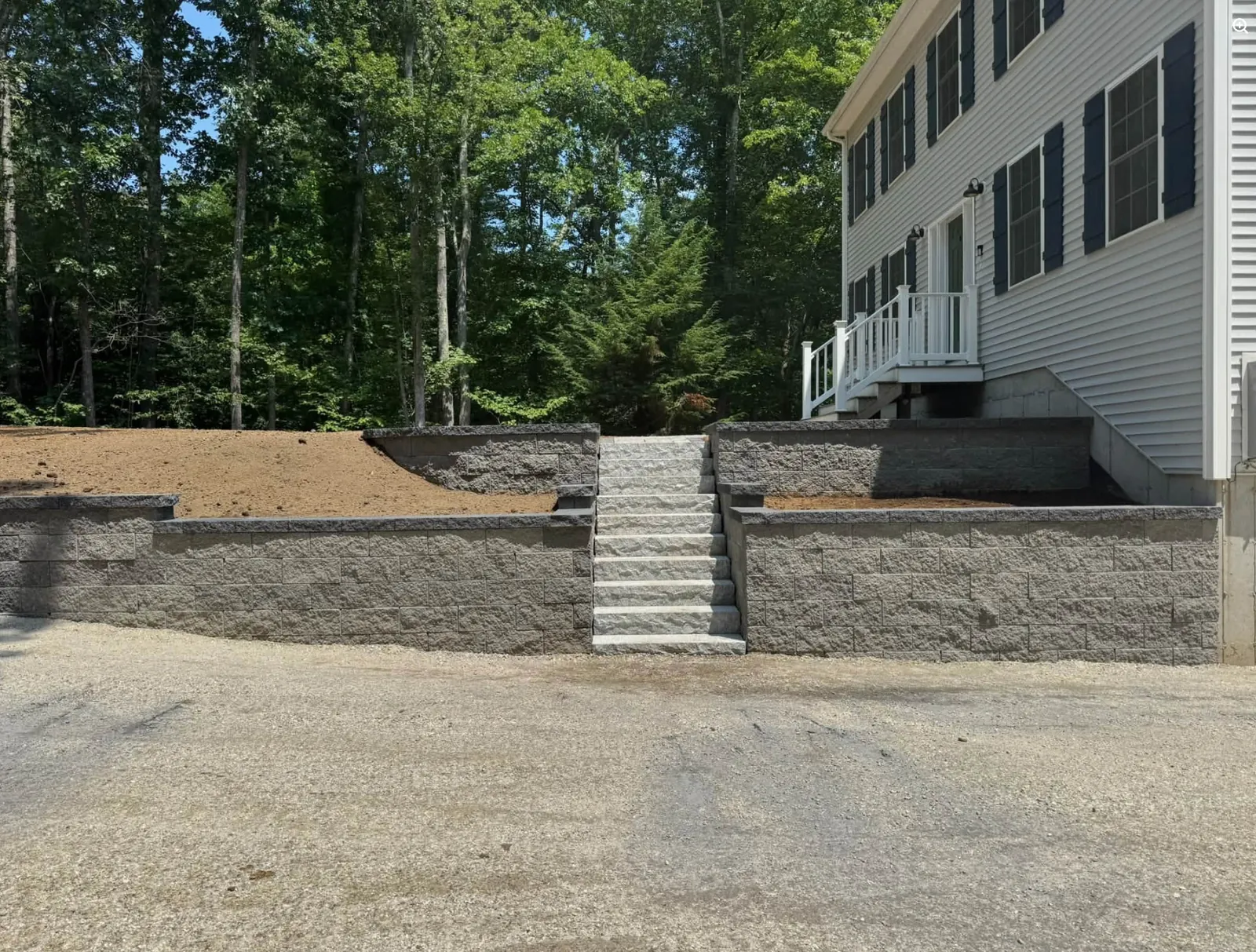 Finished retaining walls and stone steps built beside a New Hampshire home